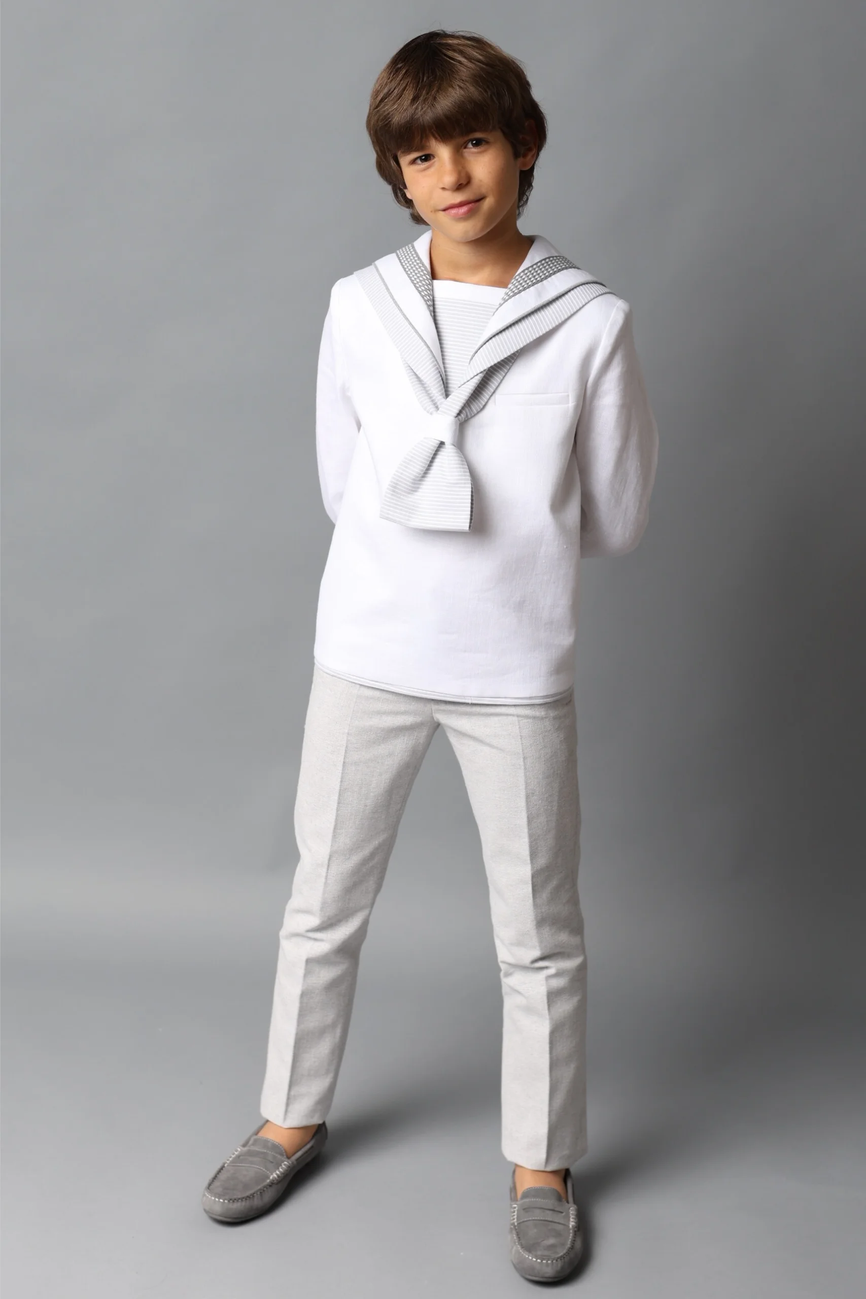 Niño con conjunto de comunión clásico de estilo marinero en blanco y gris, ideal para ceremonias de primera comunión, disponible en Marta Molina Comuniones.