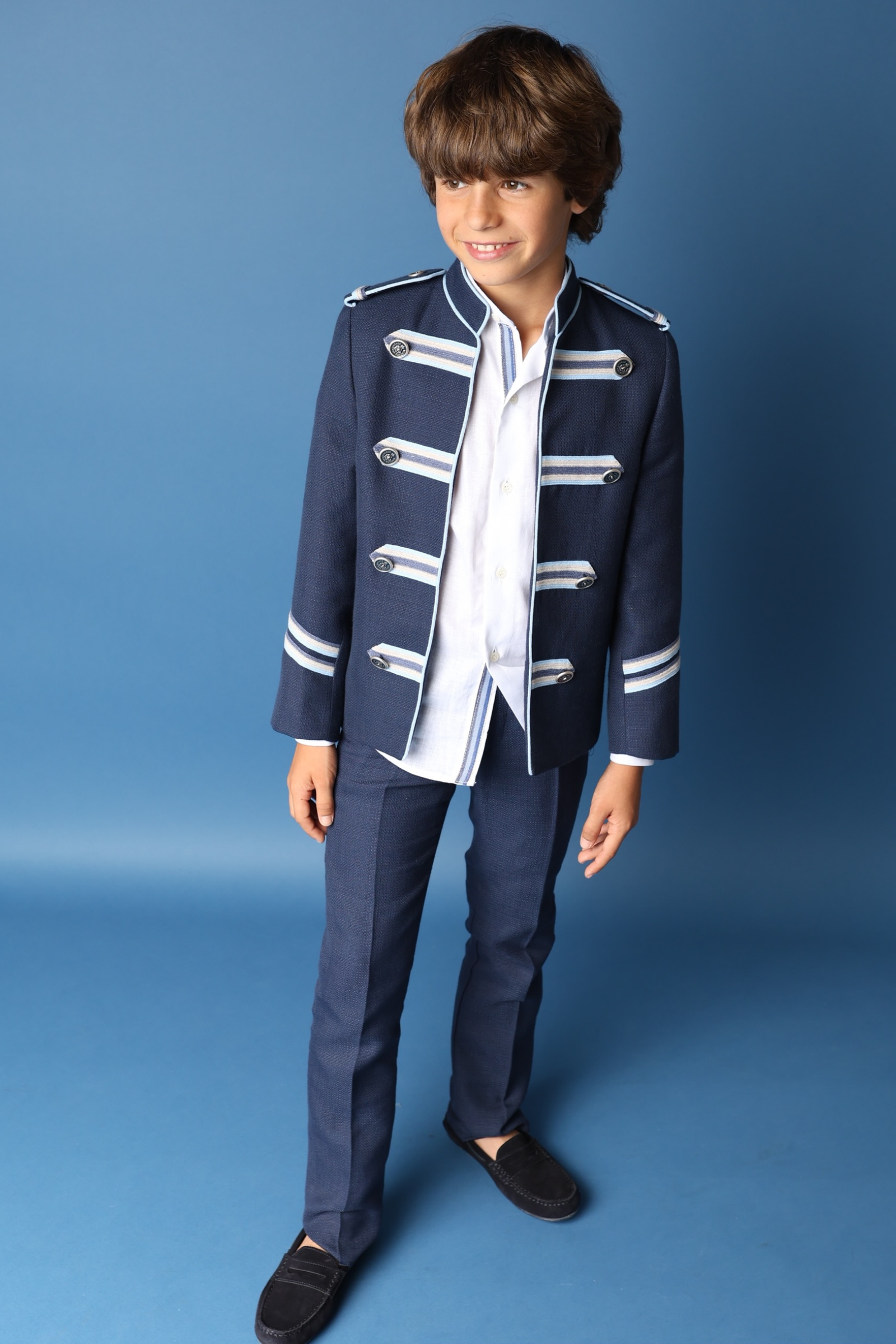 Niño con traje estilo militar en azul marino, parte de la colección de comunión 2025.