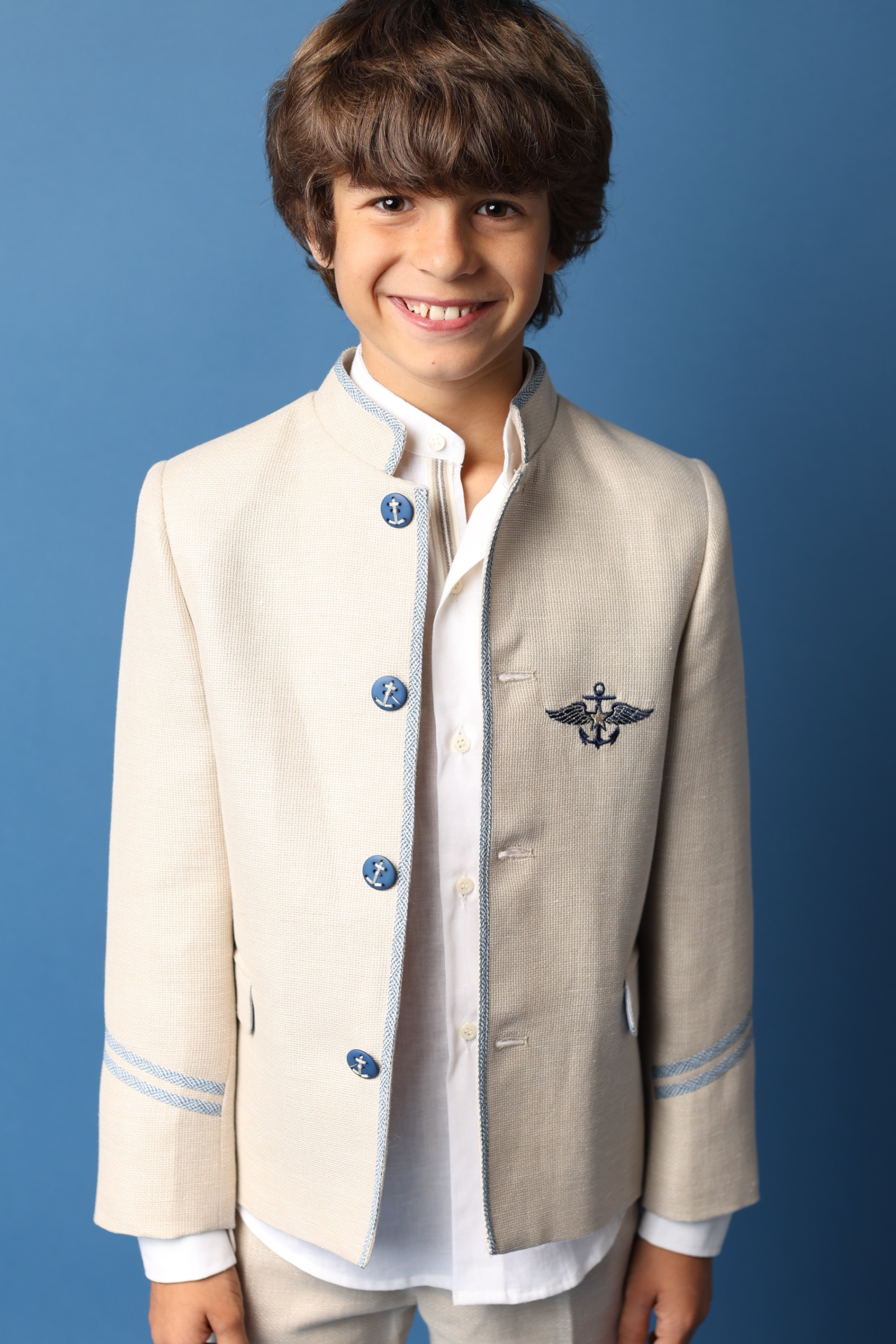 Niño con chaqueta beige estilo militar, ideal para comuniones 2025.