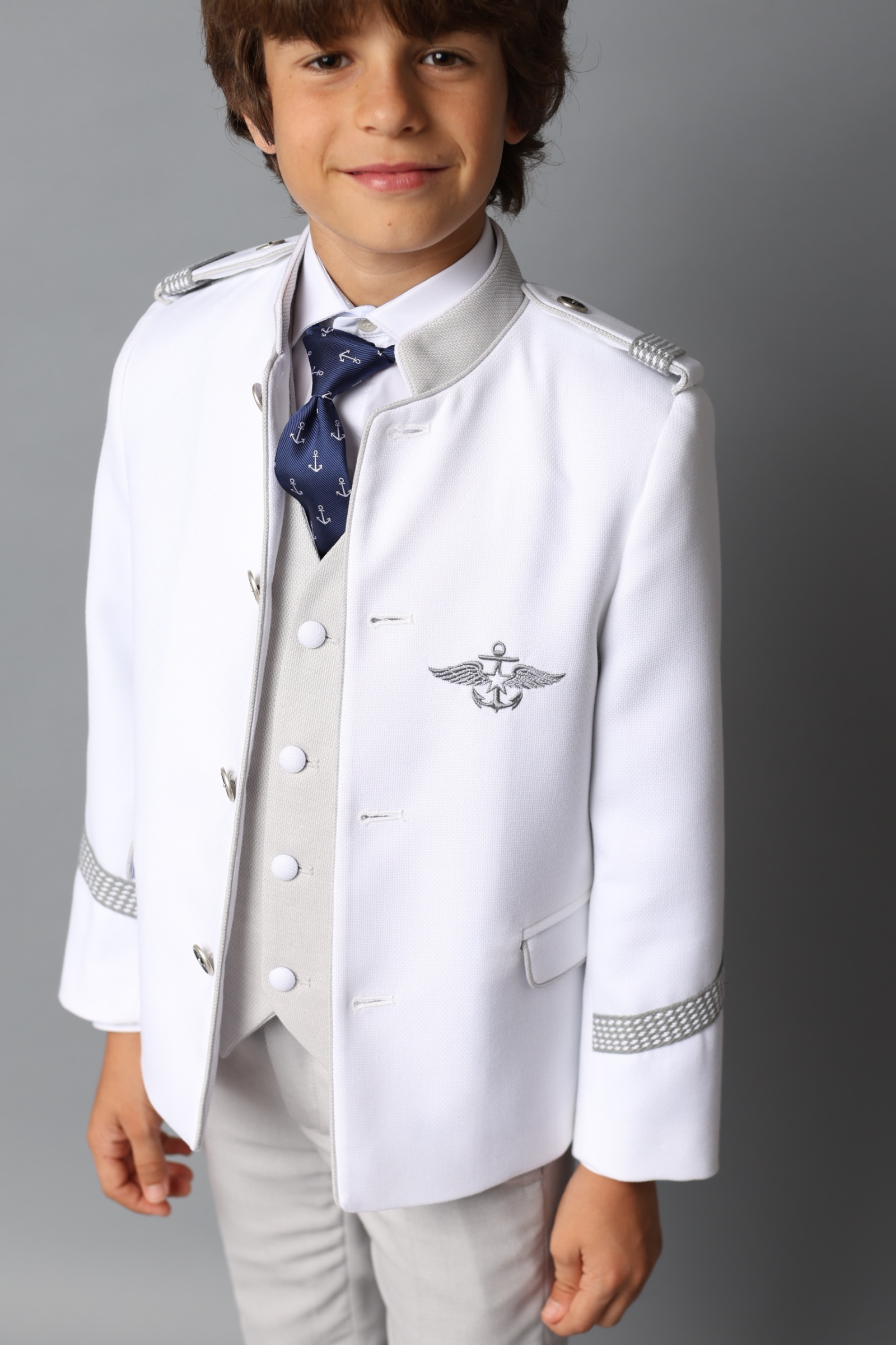Niño con traje de comunión almirante blanco con galones plateados de la colección 2025.