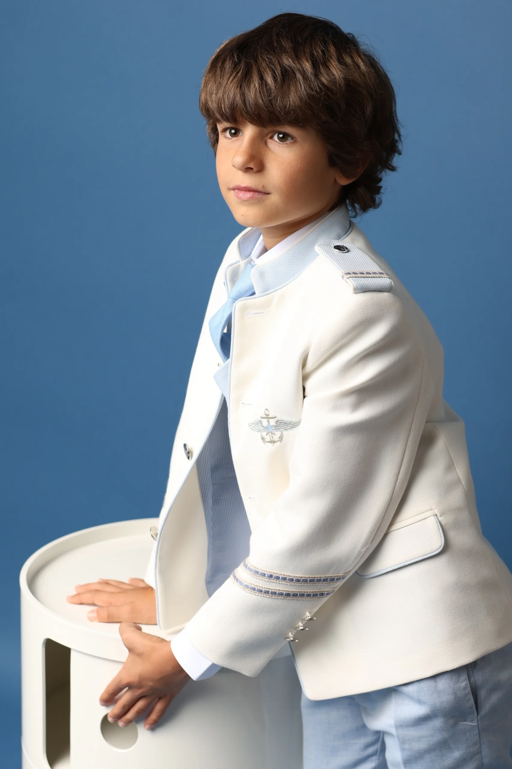 Traje Almirante Blanco y Azul Claro para Comunión 2025 Niño con traje almirante en blanco con detalles azul claro, parte de la colección 2025 de Marta Molina Comuniones.