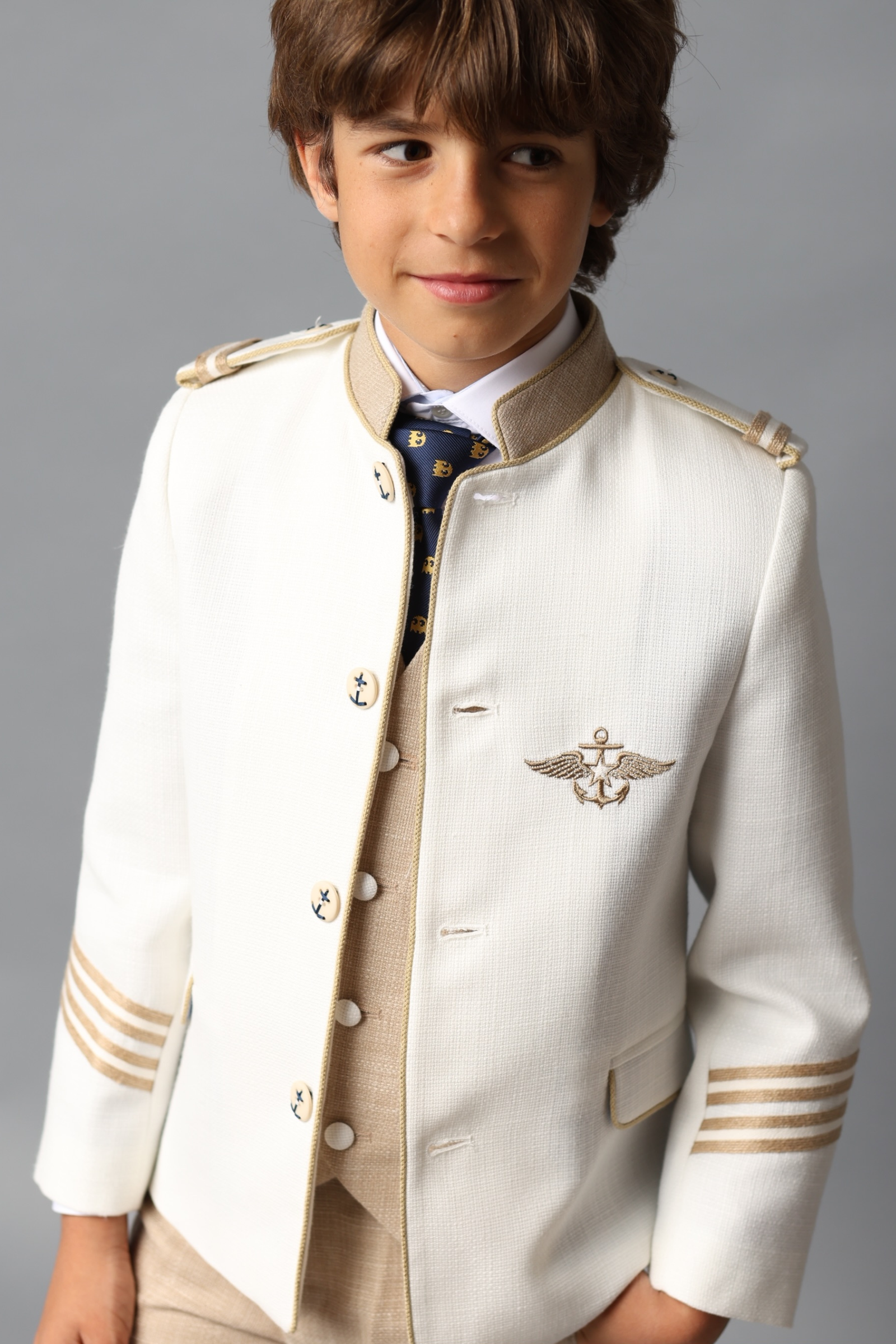 Niño con traje de comunión almirante en beige con detalles dorados, colección 2025.