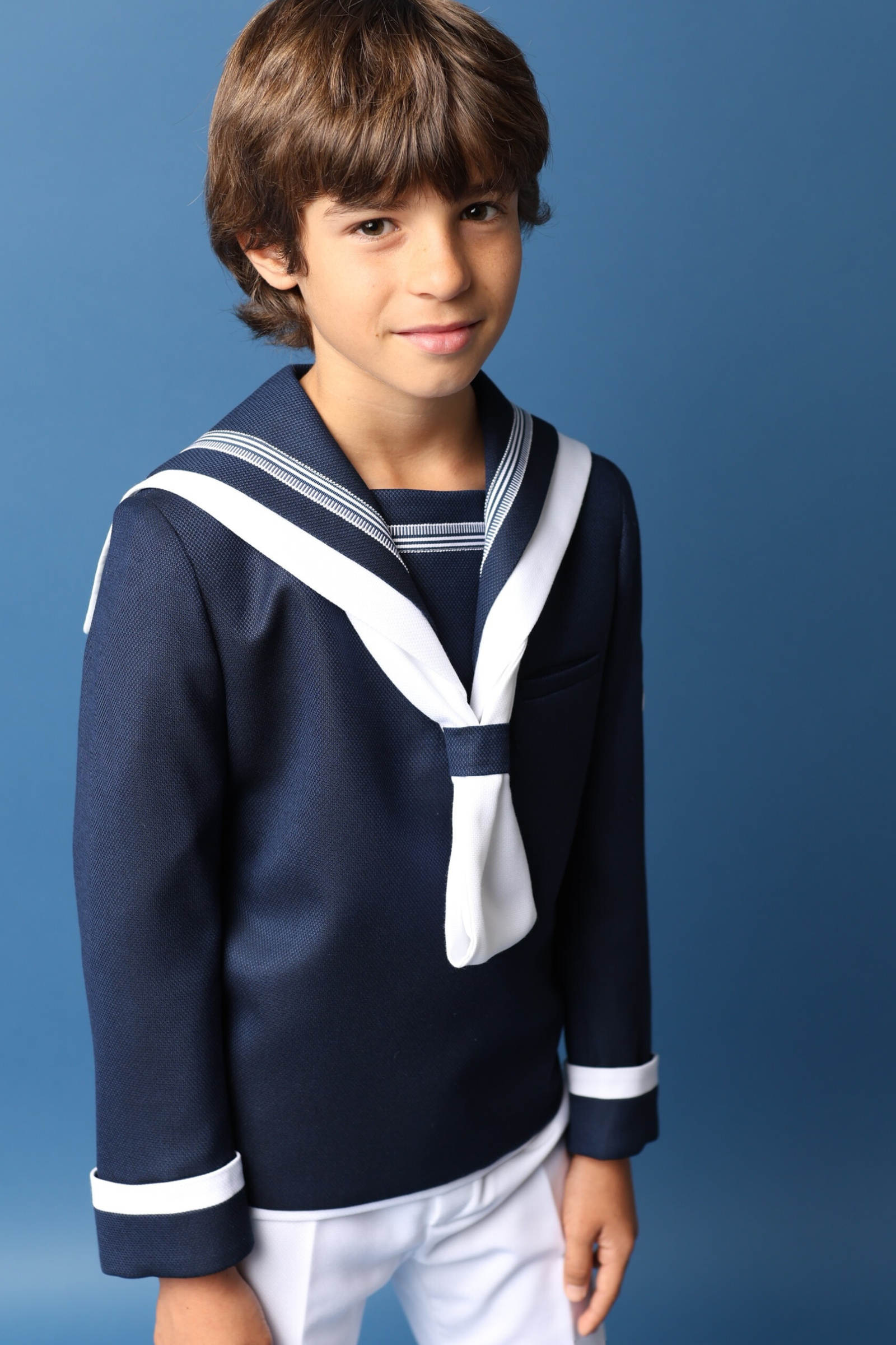 Niño con traje de comunión marinero en azul marino y blanco, ideal para la colección de comunión 2025.