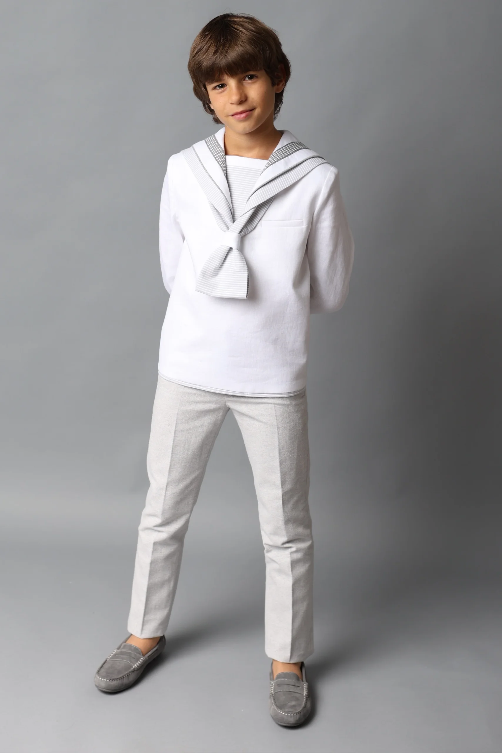 Traje de Comunión Marinero Blanco con Detalles Grises 2025 Niño con traje de comunión marinero blanco con detalles en gris, de la colección 2025.