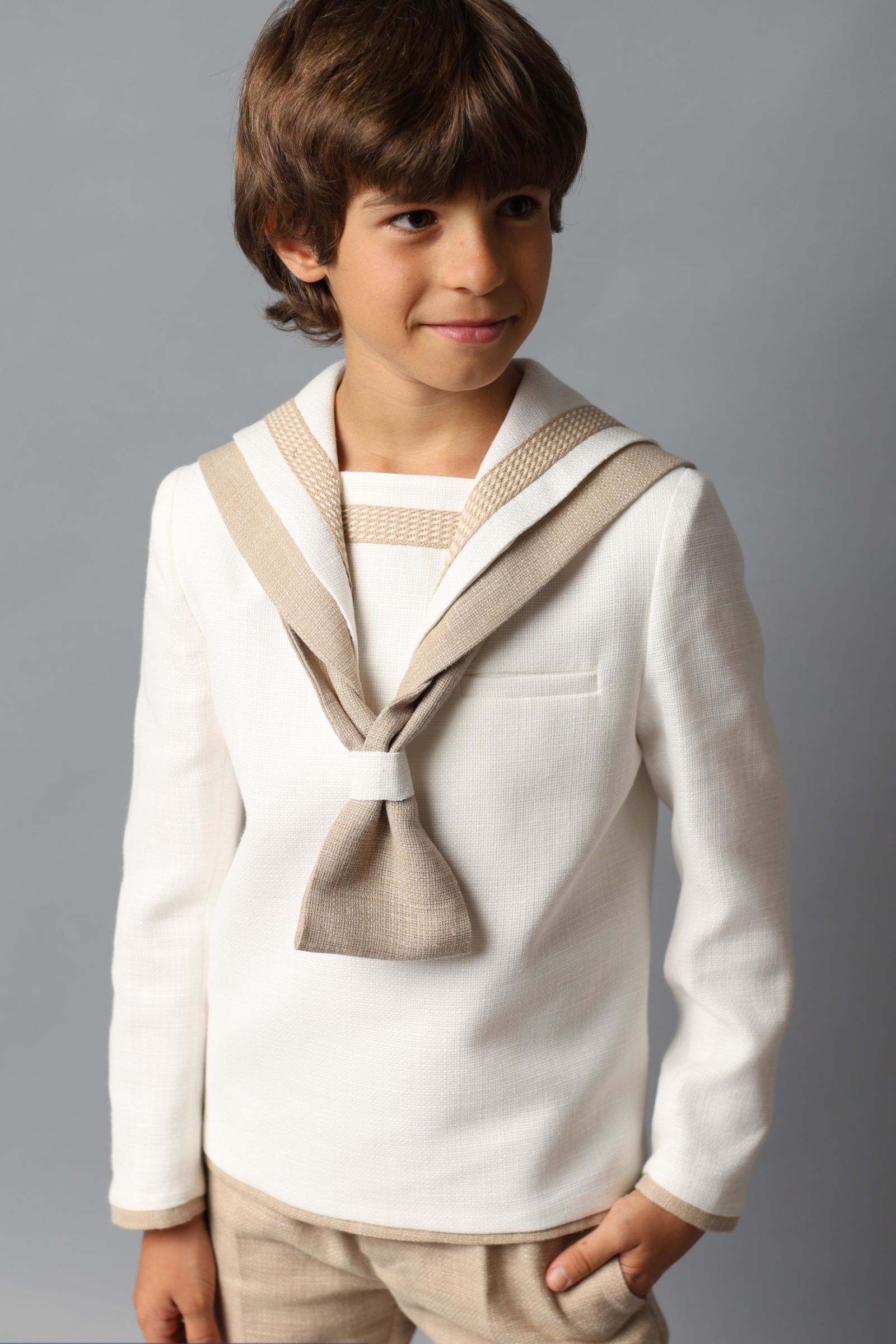 Niño con jersey de comunión marinero en tonos beige y blanco de la colección 2025.