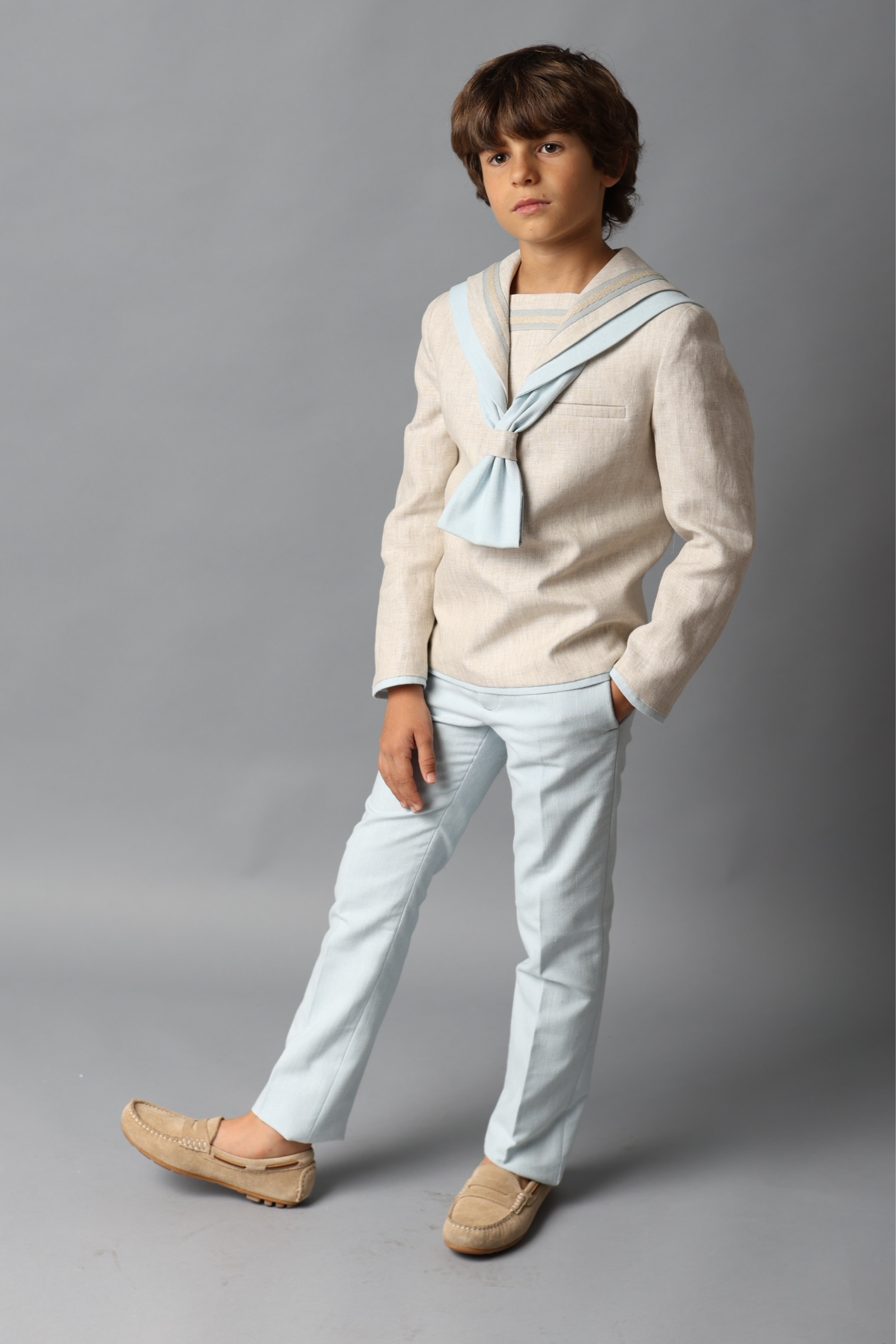 Niño con traje de comunión marinero beige con detalles azules, ideal para comuniones 2025.