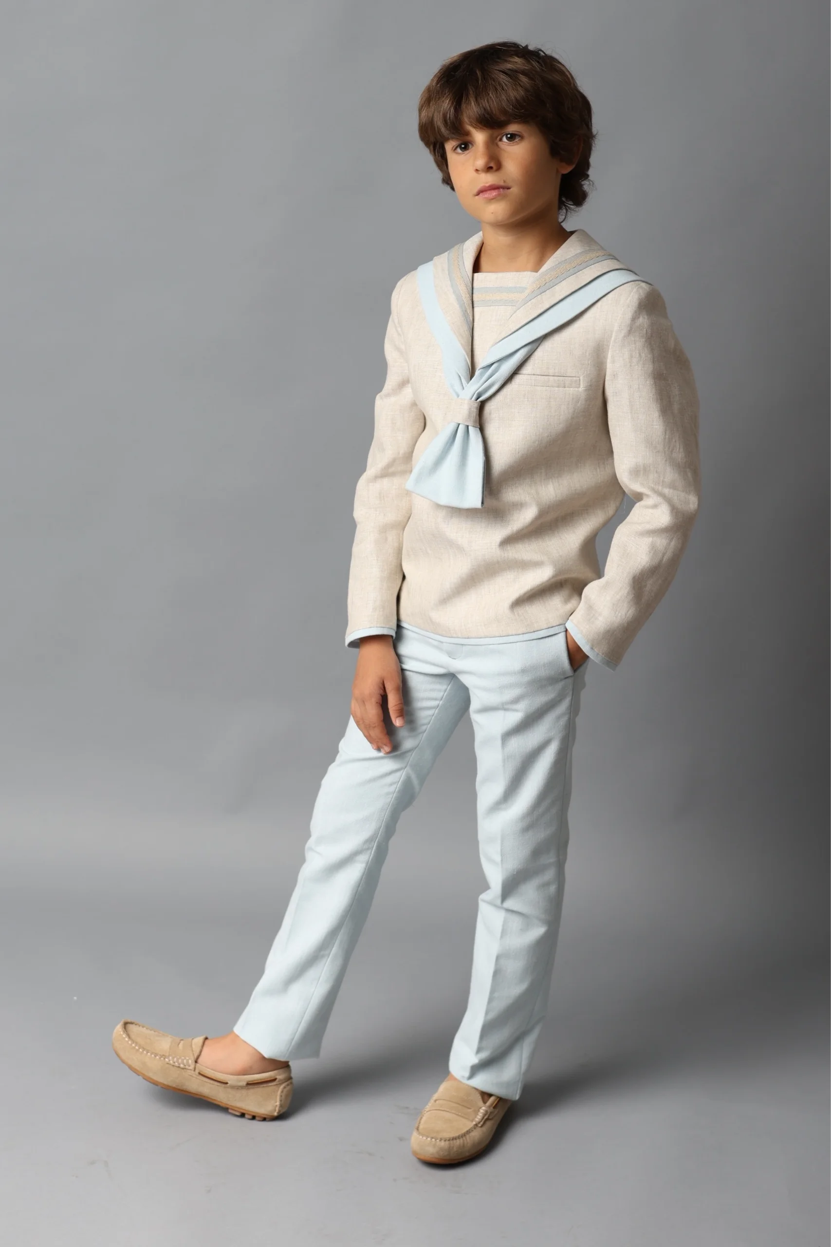 Traje de Comunión Marinero Beige 2025 Niño con traje de comunión marinero beige con detalles azules, ideal para comuniones 2025.