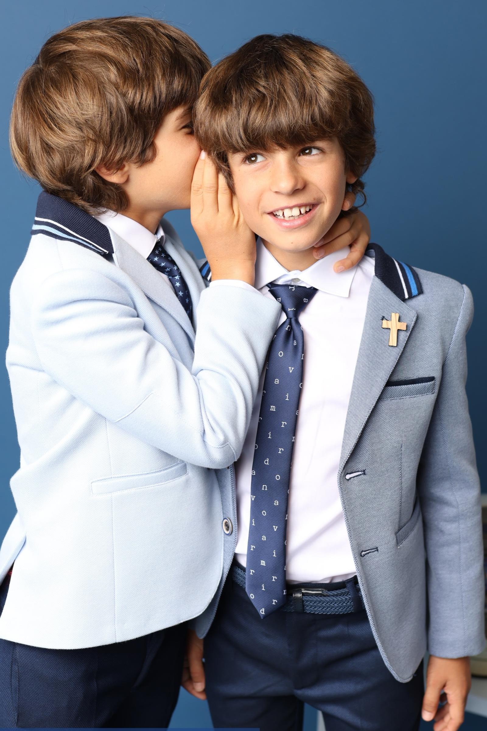 Dos niños con trajes de comunión 2025 en azul claro, uno con corbata y el otro con estilo marinero, ideales para hermanos.