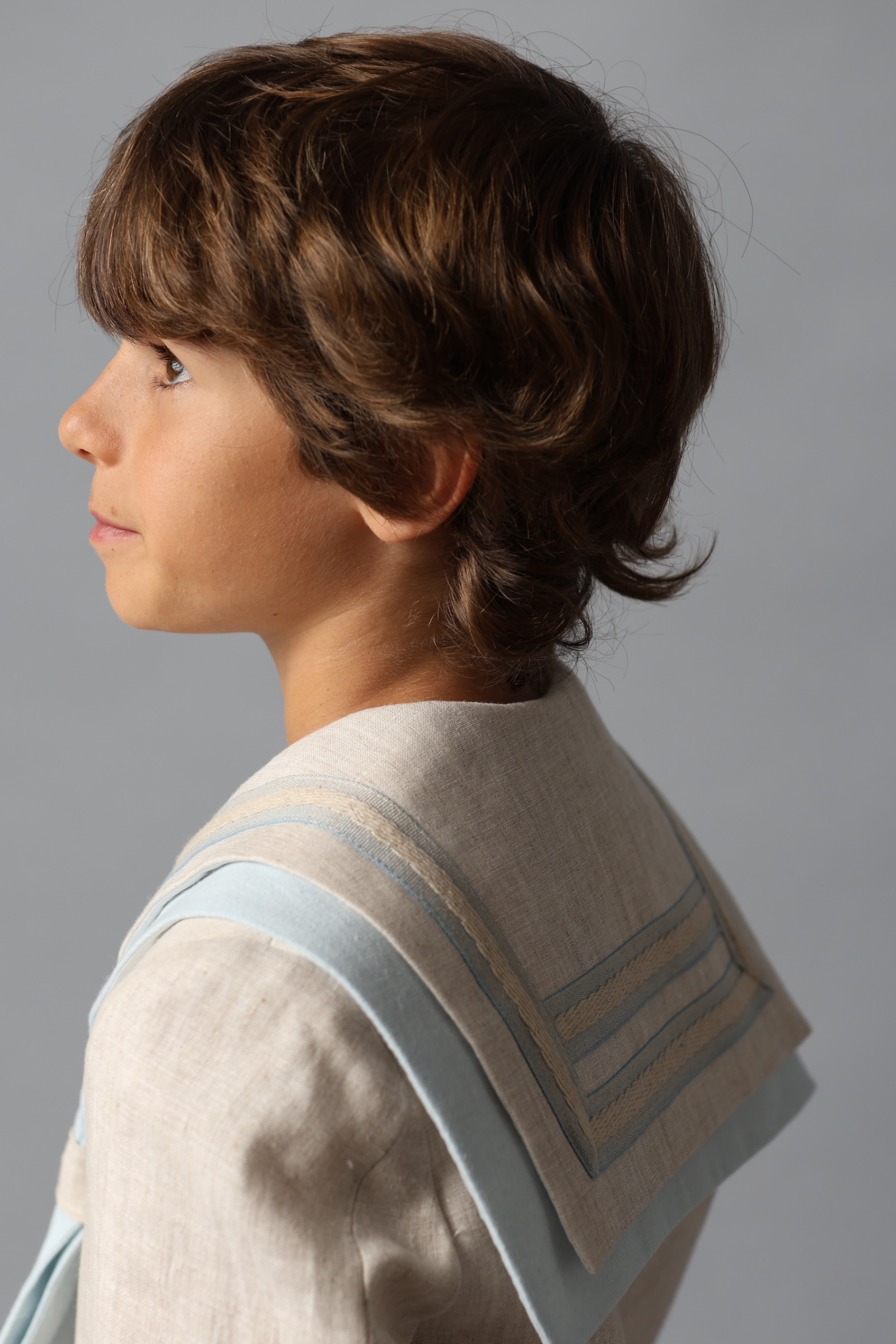 Vista lateral del detalle de un traje de comunión marinero en blanco con detalles azules, de la colección 2025.