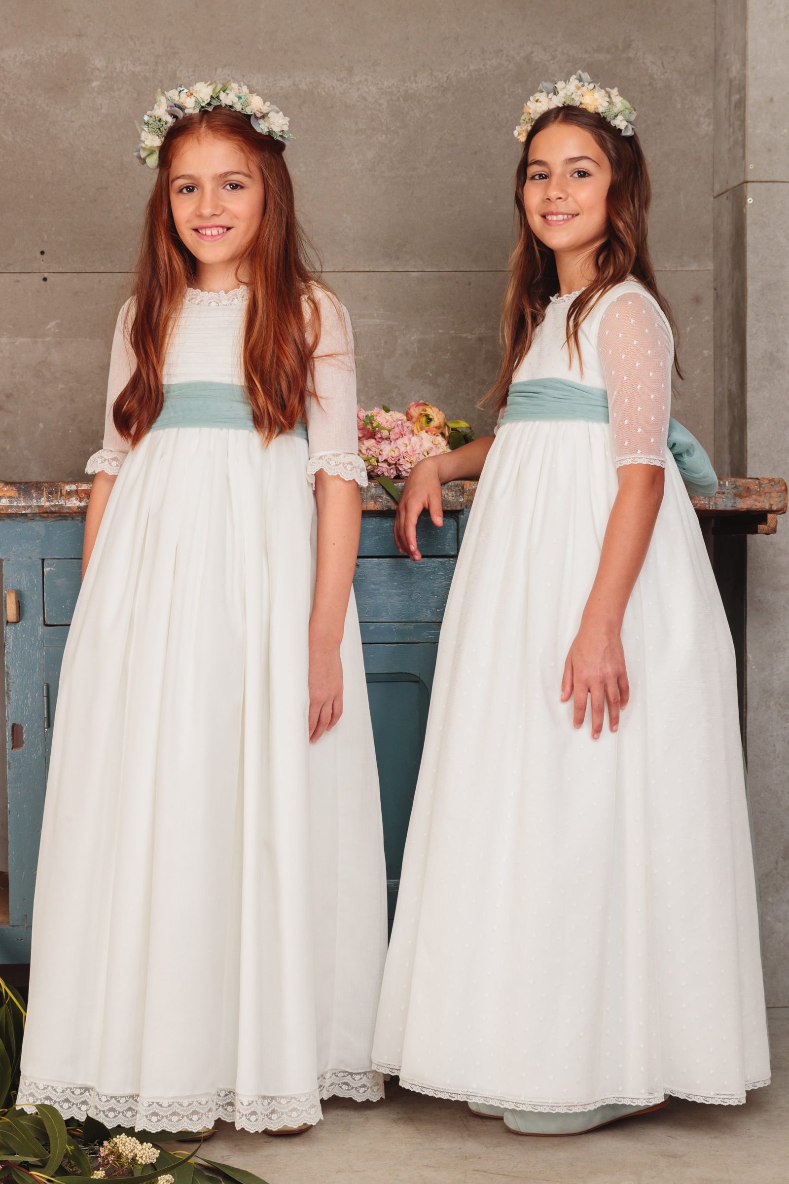 Dos vestidos de comunión niña 2025 blancos con fajín verde agua, mangas de tul y coronas de flores, exclusivos en MartaMolina.com